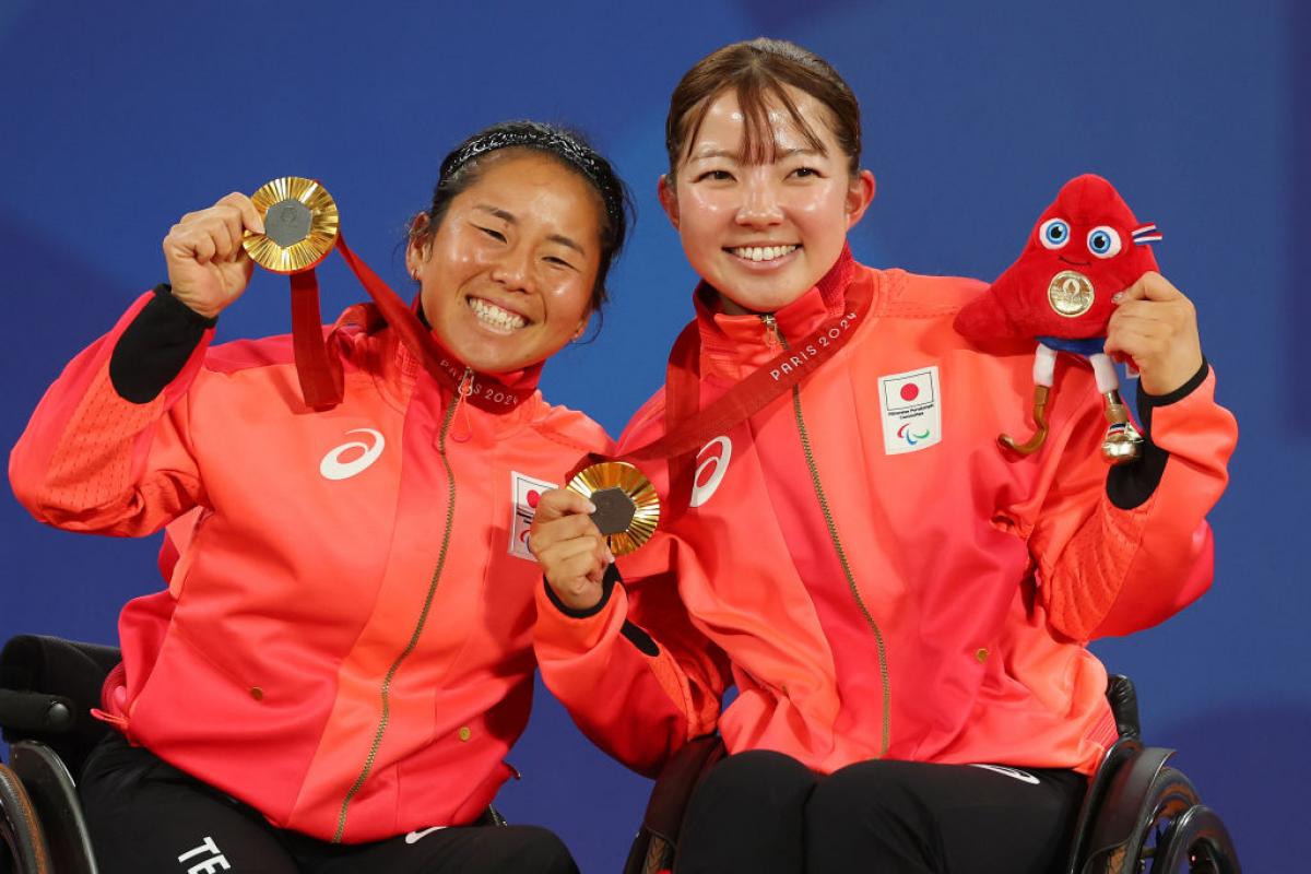 Two female athletes celebrate on the podium with gold medal